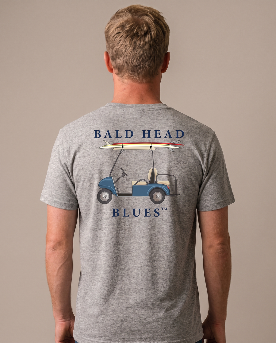 Studio back view of a man wearing the Island Tee Short Sleeve Golf Cart in Heather Grey with the Bald Head Blues cart and surfboard print